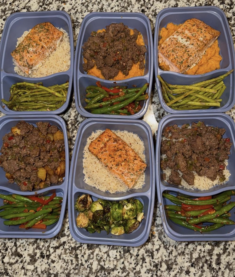 Six meal prep containers with salmon, ground beef, rice, sweet potato and vegetables